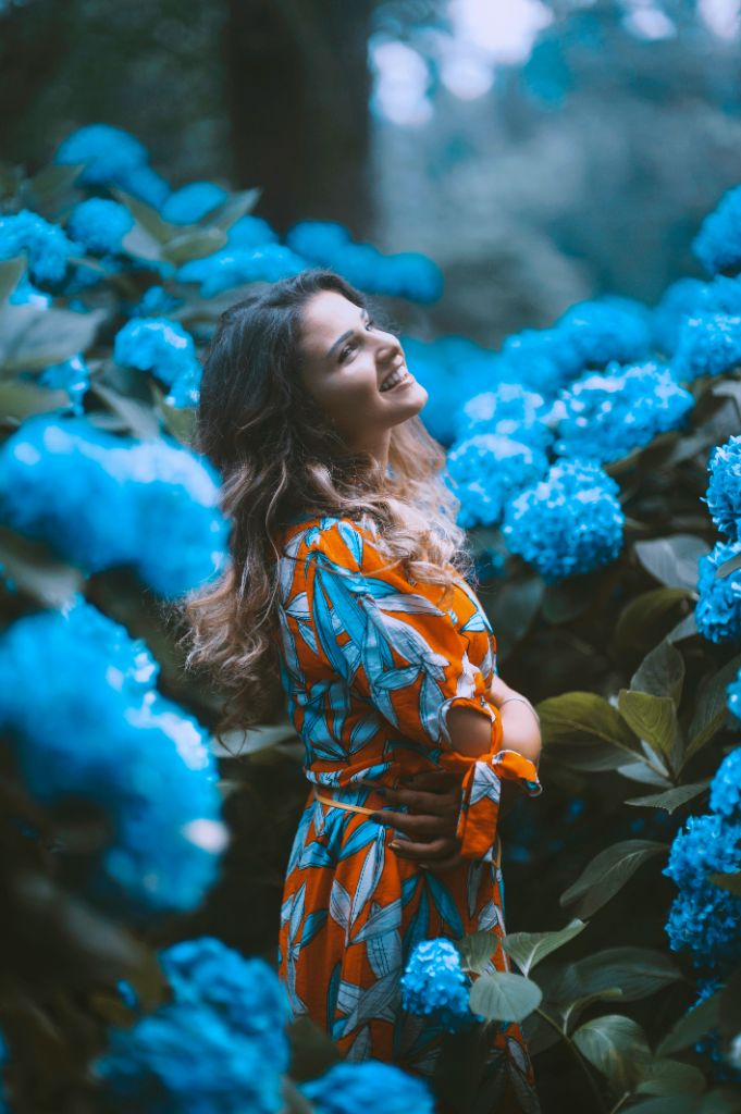 Woman smiling among blue hydrangea blossoms