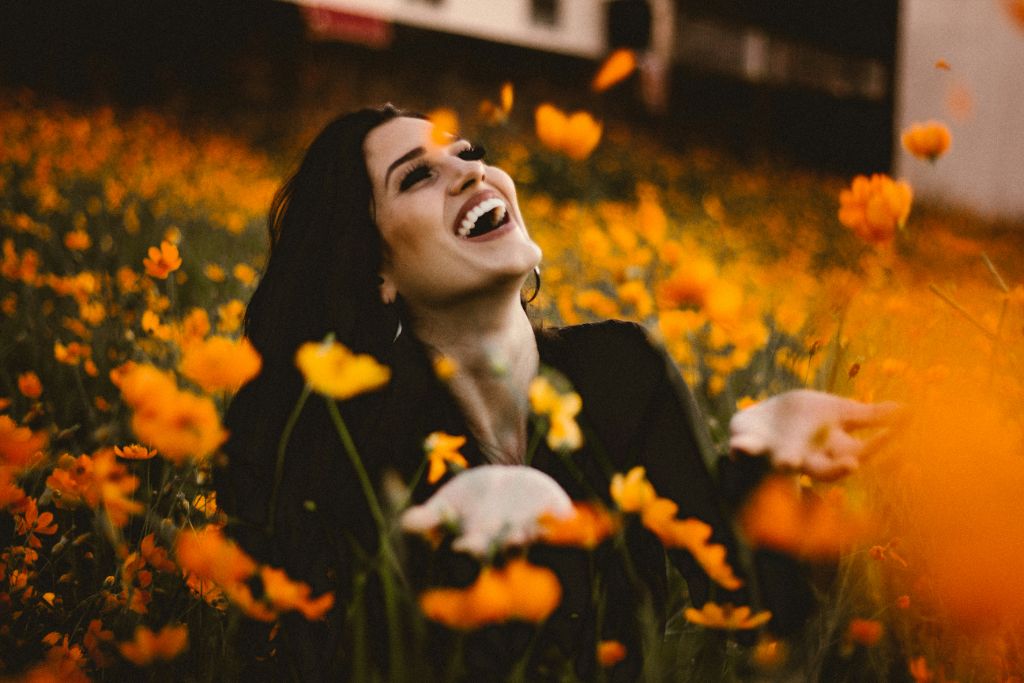 Woman laughing joyfully in a field of orange flowers