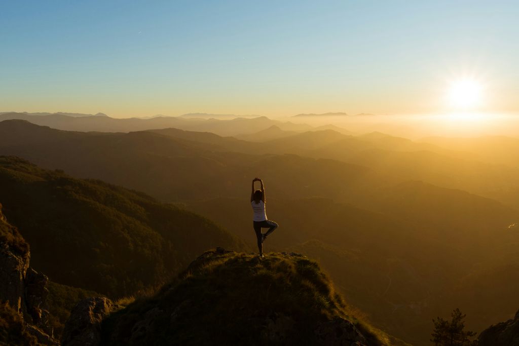 Person practicing yoga at sunrise on a mountain